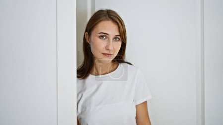 Foto de Mujer joven abriendo la puerta de pie con cara seria en casa - Imagen libre de derechos