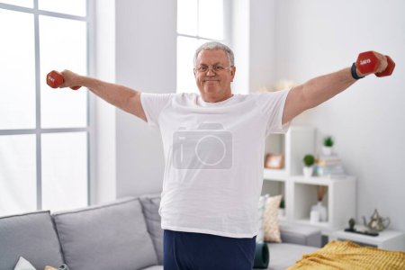 Photo for Middle age grey-haired man smiling confident using dumbbells training at home - Royalty Free Image