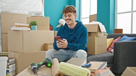 Photo for Young hispanic man using smartphone sitting on sofa at new home - Royalty Free Image