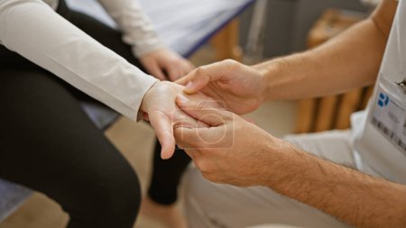 Foto de Terapeuta hombre realiza fisioterapia de la mano en paciente femenino en un centro de rehabilitación. - Imagen libre de derechos
