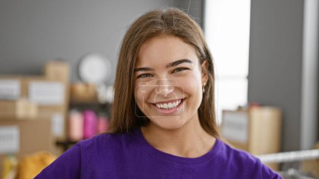 Téléchargez les photos : Confiant belle hispanique jeune femme souriant comme bénévole dans un centre de charité - en image libre de droit