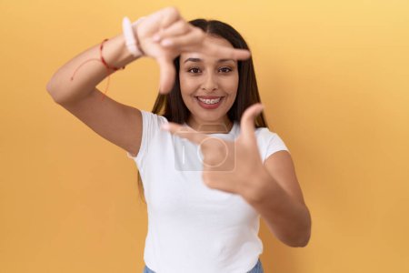 Photo for Young arab woman wearing casual white t shirt over yellow background smiling making frame with hands and fingers with happy face. creativity and photography concept. - Royalty Free Image