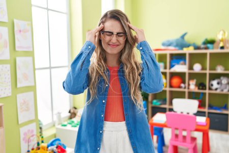 Photo for Young caucasian woman working as teacher at kindergarten suffering from headache desperate and stressed because pain and migraine. hands on head. - Royalty Free Image