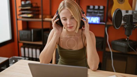 Téléchargez les photos : Jeune journaliste de radio blonde écoutant de la musique au studio de podcast - en image libre de droit