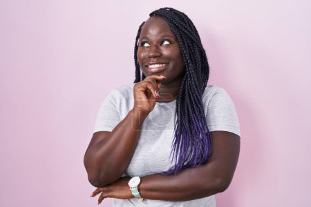 Photo for Young african woman standing over pink background with hand on chin thinking about question, pensive expression. smiling and thoughtful face. doubt concept. - Royalty Free Image