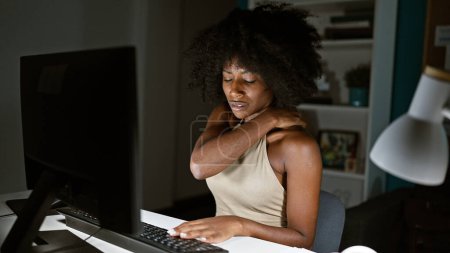 Téléchargez les photos : Femme afro-américaine ouvrière utilisant l'ordinateur souffrant de douleurs cervicales au bureau - en image libre de droit