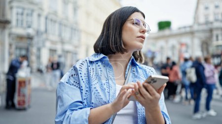 Téléchargez les photos : Jeune belle femme hispanique utilisant un smartphone attendant un taxi dans les rues de Vienne - en image libre de droit