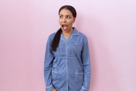 Photo for Young arab woman wearing blue pajama angry and mad screaming frustrated and furious, shouting with anger. rage and aggressive concept. - Royalty Free Image