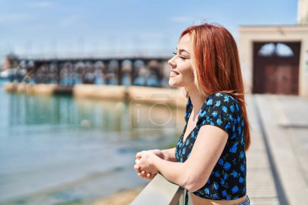 Téléchargez les photos : Jeune femme caucasienne penchée sur la balustrade regardant sur le côté à la mer - en image libre de droit
