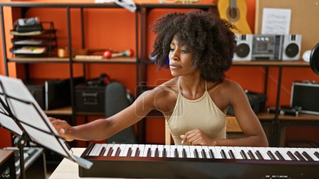 Téléchargez les photos : Musicienne afro-américaine jouant du piano lisant des partitions au studio de musique - en image libre de droit