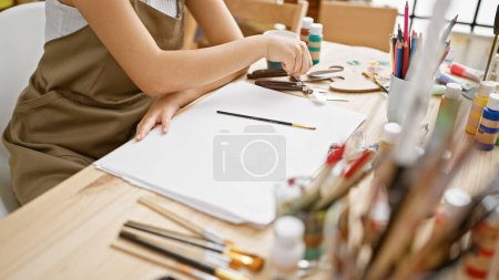 Foto de Apasionada joven artista hispana dibujando en cuaderno en medio de lecciones de pintura dentro de un estudio de arte - Imagen libre de derechos