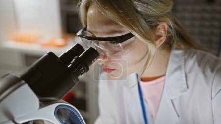 Foto de Científica rubia usando microscopio en laboratorio, mostrando conceptos de investigación, salud y educación. - Imagen libre de derechos