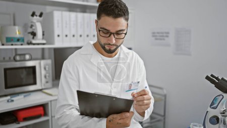 Photo for A focused man in a lab coat examines documents in a modern laboratory setting, epitomizing medical professionalism. - Royalty Free Image