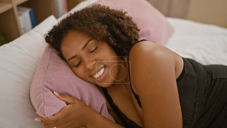 Foto de Mujer afroamericana relajándose en el dormitorio con una sonrisa - Imagen libre de derechos