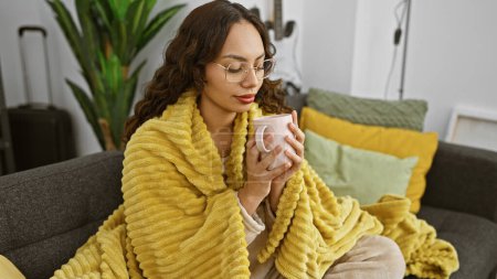Relaxed woman drinking coffee in a cozy living room with luggage suggesting travel preparation.
