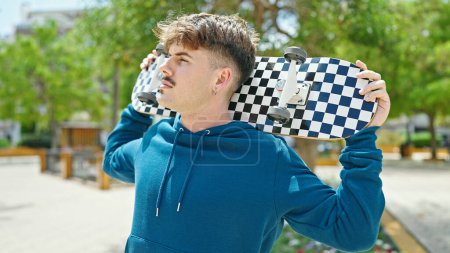 Photo for Young hispanic man holding skate with serious face at park - Royalty Free Image