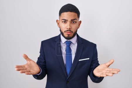 Photo for Young hispanic man wearing business suit and tie clueless and confused with open arms, no idea concept. - Royalty Free Image