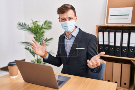 Photo for Young man business worker wearing medical mask working at office - Royalty Free Image