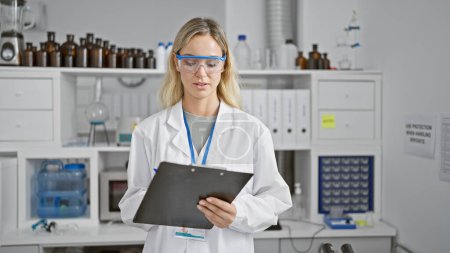 Foto de Una joven científica en un laboratorio revisa los datos en un portapapeles, representando profesionalismo y enfoque en un entorno clínico. - Imagen libre de derechos