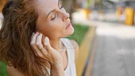 Photo for A contemplative young woman enjoys a peaceful moment in an outdoor park setting, with a touch of elegance. - Royalty Free Image
