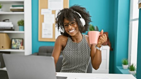 Foto de Trabajadora de negocios afroamericana escuchando música bebiendo café en la oficina - Imagen libre de derechos