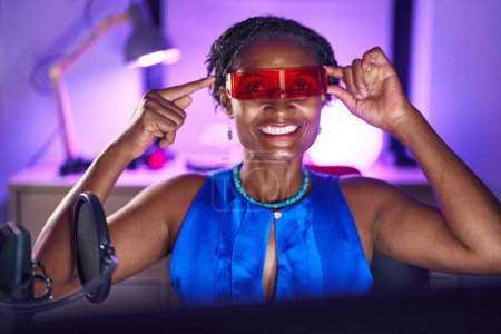 Téléchargez les photos : Femme africaine avec dreadlocks jouer à des jeux vidéo portant des lunettes de réalité virtuelle souriant heureux pointant avec la main et le doigt - en image libre de droit