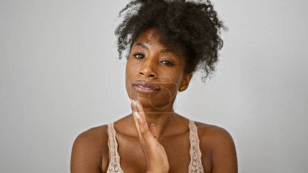 Téléchargez les photos : Femme afro-américaine portant lingerie toucher le visage sur fond blanc isolé - en image libre de droit