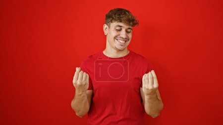 Photo for Cheery young hispanic man confidently flashing money sign, isolated over vibrant red background! - Royalty Free Image