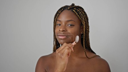 Photo for African american woman smiling confident massaging face with skin gym over isolated white background - Royalty Free Image