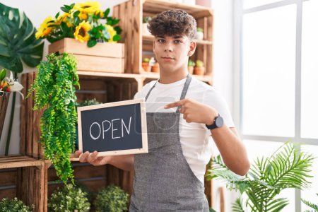 Photo for Hispanic teenager working at florist holding open sign smiling happy pointing with hand and finger - Royalty Free Image