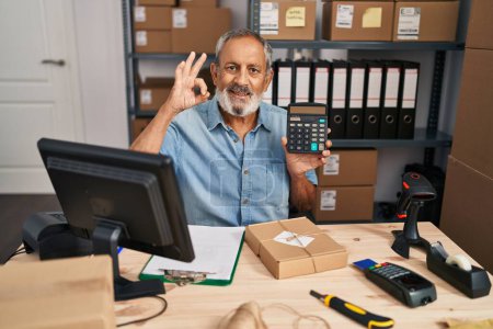 Foto de Alegre hombre mayor gesto 'bien' signo con los dedos, sonriente expresión amistosa de éxito en la oficina con calculadora - Imagen libre de derechos