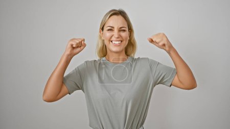Photo for Portrait of a young, cheerful, caucasian woman flexing her muscles confidently against a white background. - Royalty Free Image