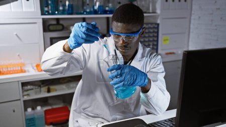 Foto de Científico africano que trabaja con productos químicos en un entorno de laboratorio, lo que refleja profesionalidad y precisión como hombre examina una solución. - Imagen libre de derechos
