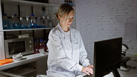 Téléchargez les photos : Une jeune femme scientifique travaille sur ordinateur dans un laboratoire moderne. - en image libre de droit