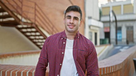 Young, confident hispanic man caught in a joyful smiling expression, happily standing outdoors on an urban street. a cheerful, attractive guy radiating positivity and confidence.