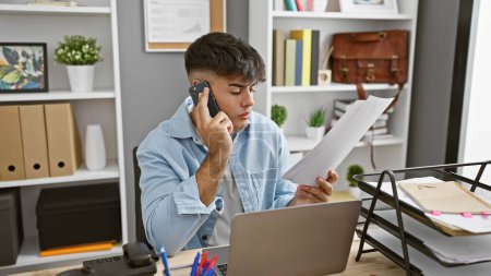 Photo for Young hispanic man business worker talking on smartphone reading document at the office - Royalty Free Image