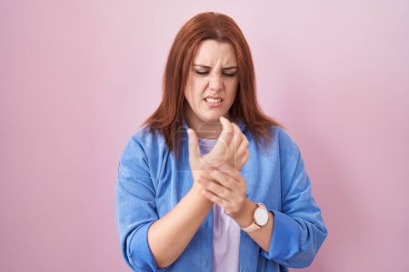 Photo for Young hispanic woman with red hair standing over pink background suffering pain on hands and fingers, arthritis inflammation - Royalty Free Image