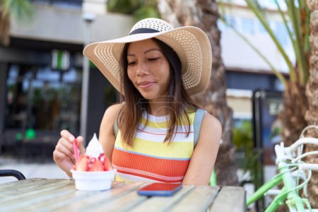 Photo for Young asian woman tourist eating ice cream sitting on table at coffee shop terrace - Royalty Free Image