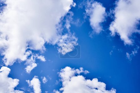 Photo for Vast blue sky adorned with fluffy white clouds and a distant tiny airplane soaring high. - Royalty Free Image
