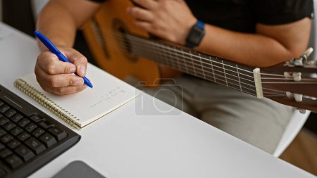 Photo for Passionate young latin man, a musician in the heart of his craft, composing a melody while holding a classical guitar in a cozy music studio - Royalty Free Image