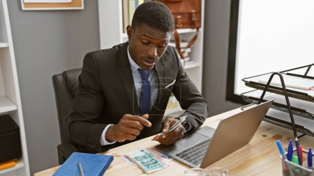 Photo for Focused african man counting chinese yuan in a modern office setting - Royalty Free Image