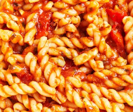 Nahaufnahme von Fusilli-Pasta in Tomatensauce, was auf eine köstliche italienische Mahlzeit ohne Anwesenheit von Personen hindeutet.