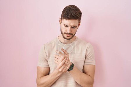 Photo for Hispanic man with beard standing over pink background suffering pain on hands and fingers, arthritis inflammation - Royalty Free Image