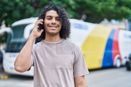 Photo for Young latin man smiling confident talking on the smartphone at bus station - Royalty Free Image