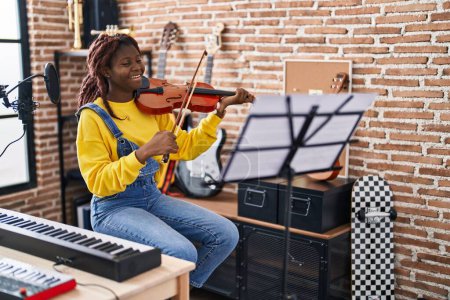 Téléchargez les photos : Africaine américaine musicien souriant confiant jouer du violon au studio de musique - en image libre de droit