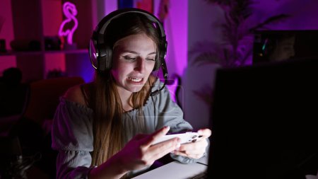 Foto de Mujer joven enfocada jugando videojuegos en una sala de juegos oscura en casa. - Imagen libre de derechos