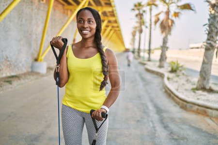 Téléchargez les photos : African american woman using elastic band training at street - en image libre de droit