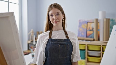 Téléchargez les photos : Jeune artiste blonde souriante confiante debout au studio d'art - en image libre de droit