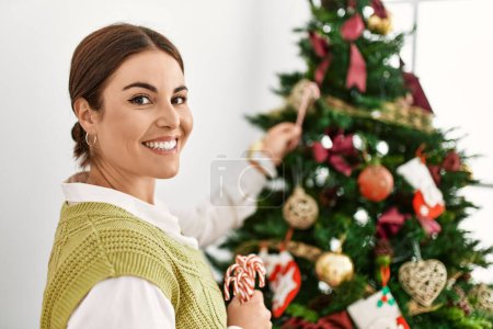 Photo for Young beautiful hispanic woman smiling confident decorating christmas tree at home - Royalty Free Image
