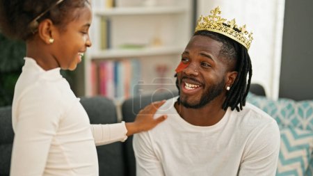 African american father and daughter wearing king crown and baggy eyes pad at home